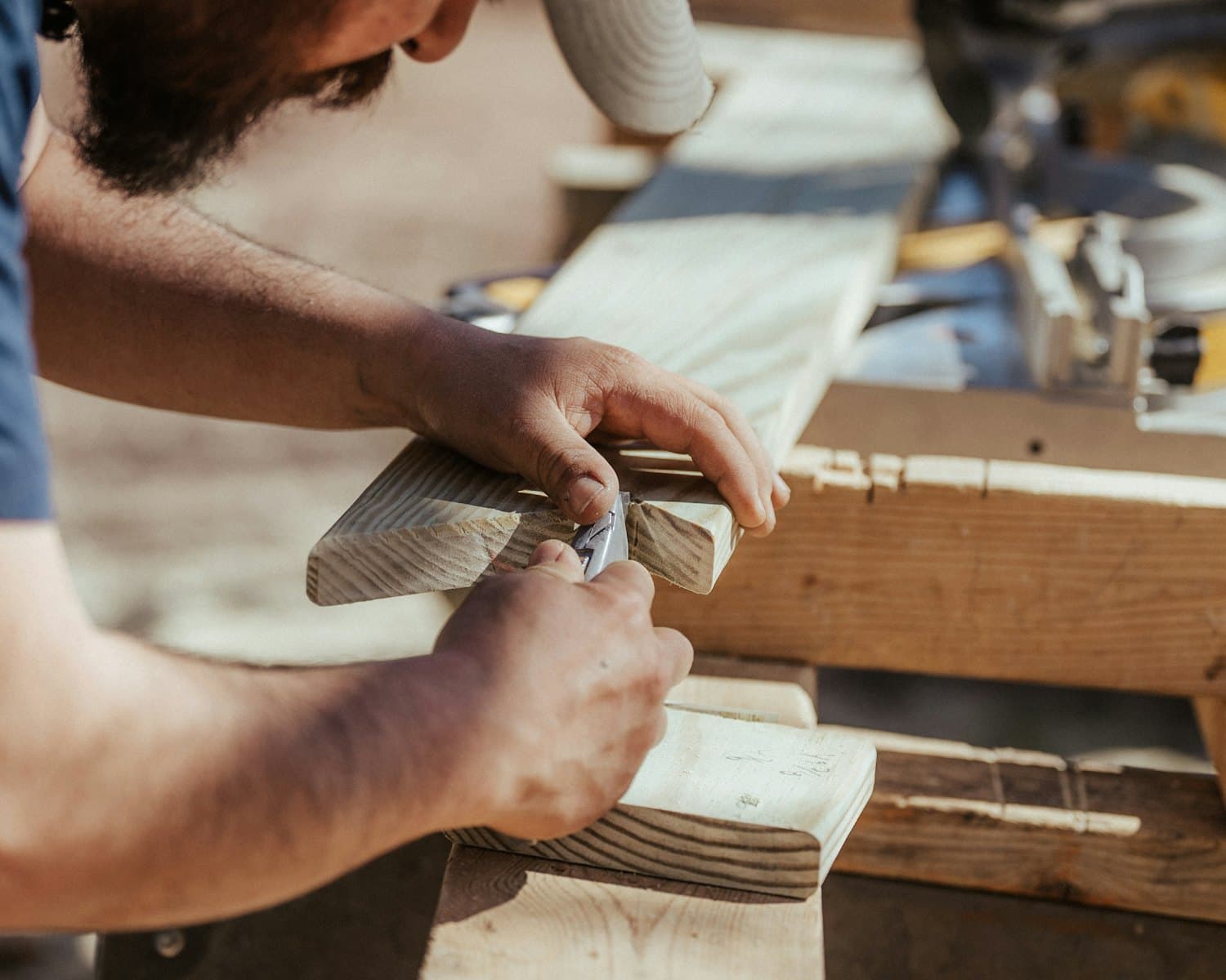 A tradesperson working a length of timber by hand on a bench